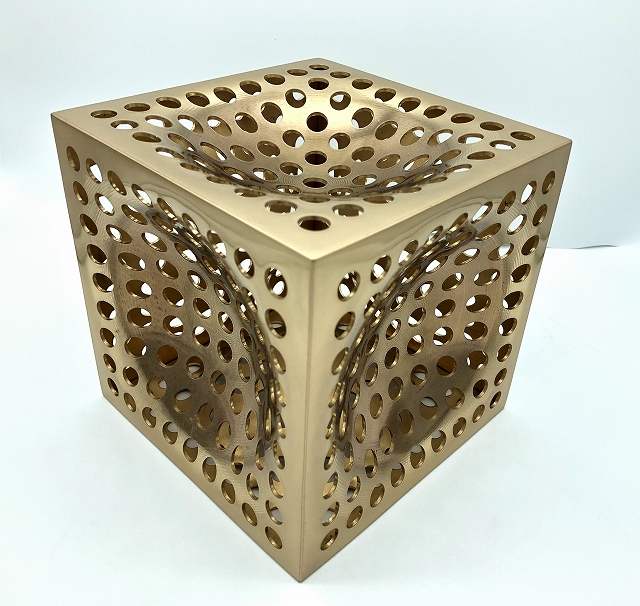 A bronze cube with indented and punched metal panels